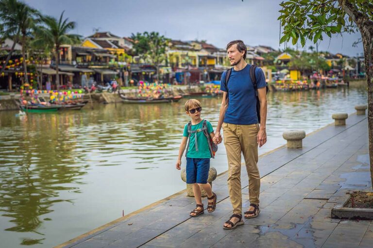 Vader en zoon wandelend langs de rivier in Hoi An tijdens een familierondreis in Vietnam