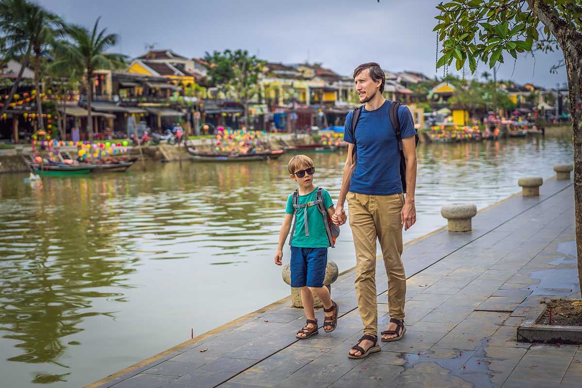 Vader en zoon wandelend langs de rivier in Hoi An tijdens een familierondreis in Vietnam