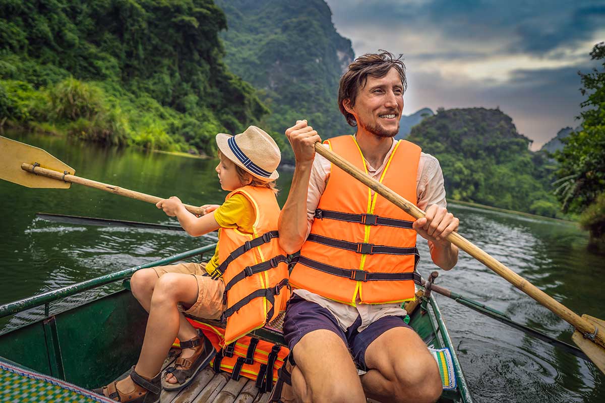 Vader en kind kajakkend in Ninh Binh tussen kalksteenbergen tijdens een familierondreis in Vietnam