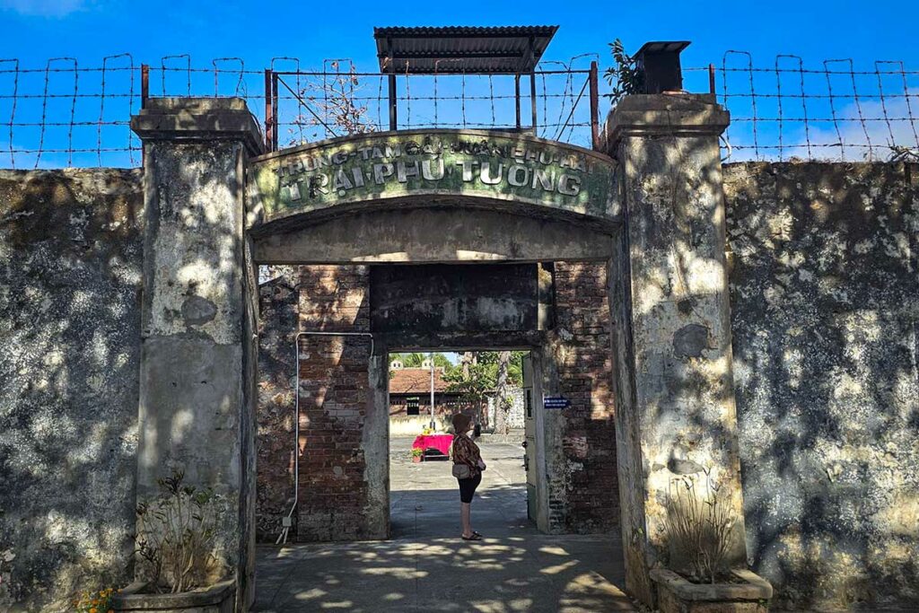 Ingang van de French Tiger Cages in Con Dao met prikkeldraad en wachttoren, beruchte gevangenis uit de Vietnamoorlog