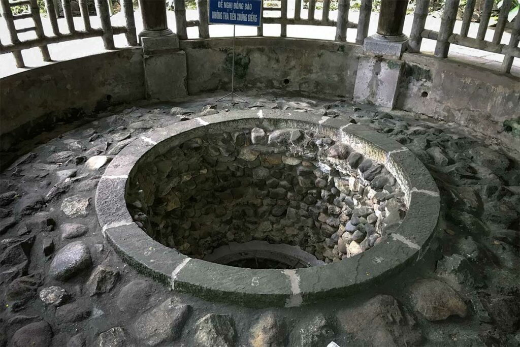 Ronde stenen waterput bij de Gieng Tempel in het Hung Kings complex in Phu Tho, omgeven door een overdekte structuur.