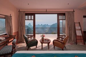 Interieur van een bungalowkamer bij Ha Giang Aya Lodge met balkon en uitzicht over de bergen van Ha Giang in Noord-Vietnam