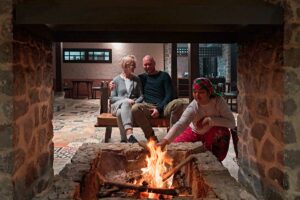 Gasten en Hmong medewerker bij het haardvuur in het restaurant van Ha Giang Aya Lodge tijdens een gezellige avond