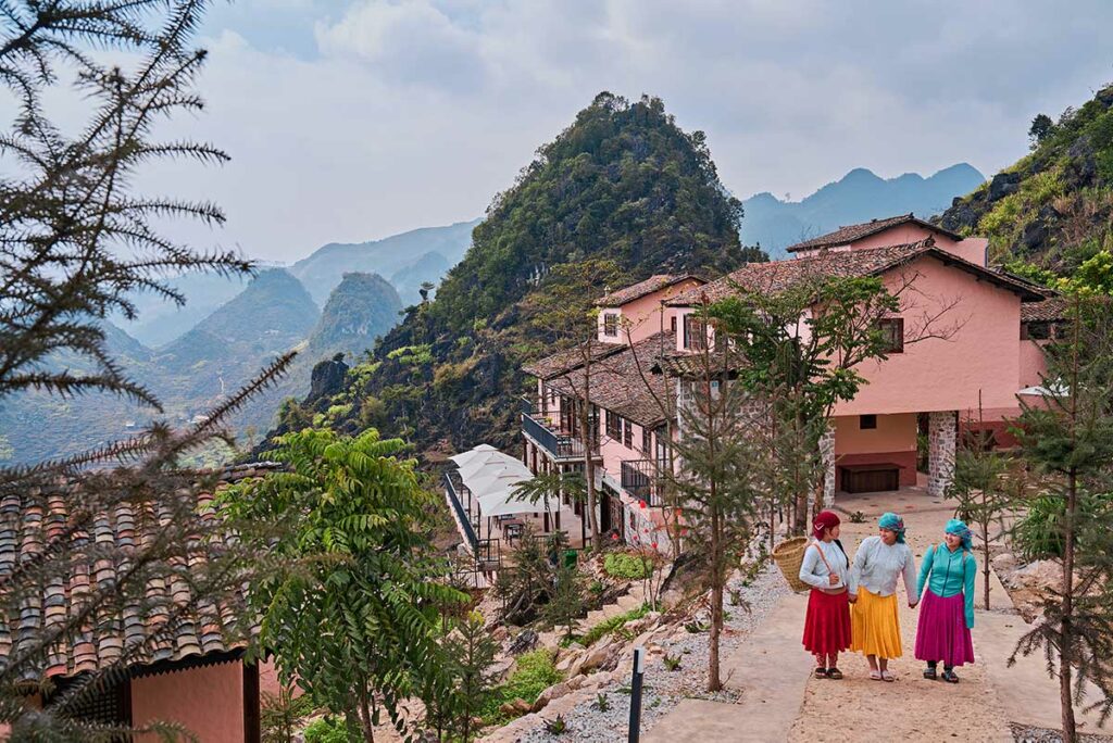 Hmong medewerkers van Ha Giang Aya Lodge wandelen over het terrein van de lodge in het berglandschap van Ha Giang