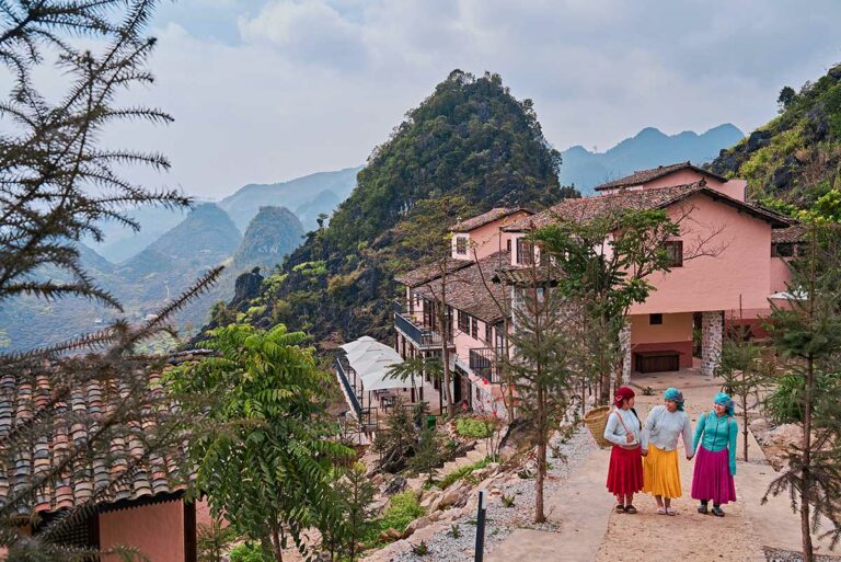 Hmong medewerkers van Ha Giang Aya Lodge wandelen over het terrein van de lodge in het berglandschap van Ha Giang