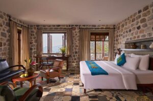 Suite kamer bij Ha Giang Aya Lodge met natuurstenen muren, zithoek en uitzicht op de bergen van Ha Giang