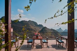 Restaurantterras van Ha Giang Aya Lodge met tafels en stoelen en uitzicht over het berglandschap van Ha Giang