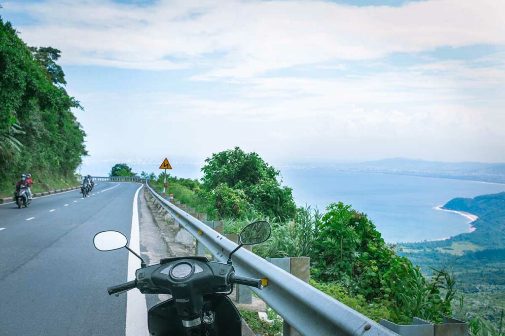 Scooter rijden over de Hai Van Pass met uitzicht op zee en bochtige bergweg in Vietnam