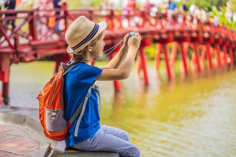 Hanoi met kinderen bij Hoan Kiem Lake terwijl een jongen foto’s maakt van de rode brug