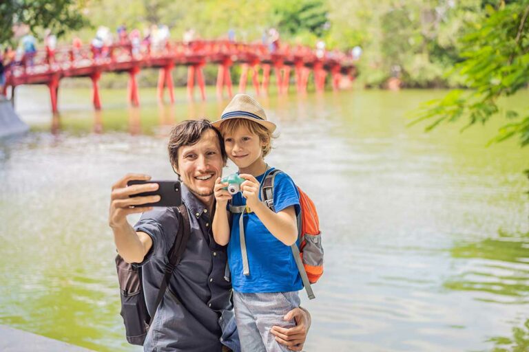 Hanoi met kinderen bij Hoan Kiem Lake met vader en zoon voor de rode Huc Bridge