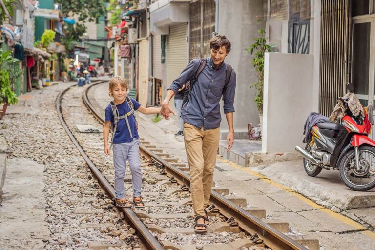 Hanoi met kinderen wandelend over de bekende Train Street tussen huizen en spoorrails