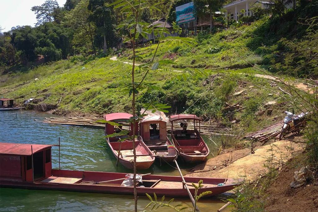 Kleine boten langs een lokaal dorp aan Hoa Binh Lake met groene heuvels op de achtergrond