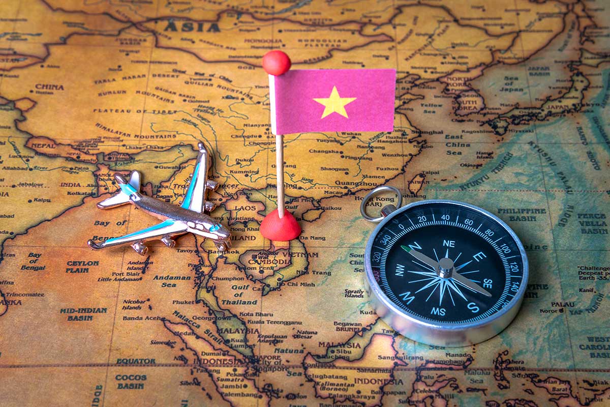 Vliegtuigmodel en kompas op kaart van Vietnam met Vietnamese vlag gemarkeerd als reisbestemming in Zuidoost-Azië