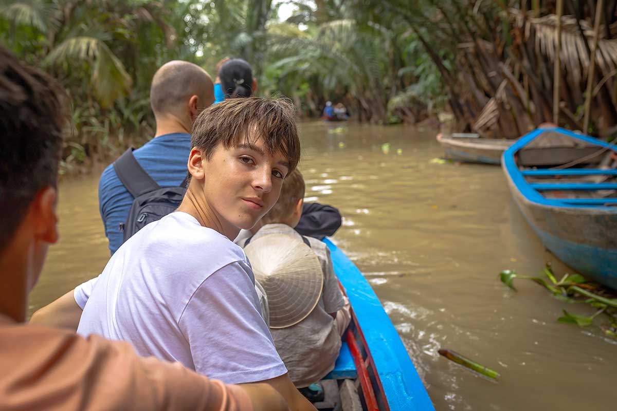 Familie met kinderen tijdens boottocht in de Mekong Delta langs dorpjes en vissersboten