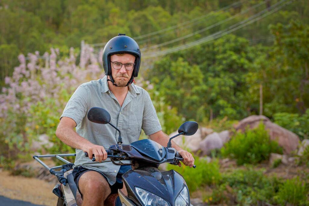 Reiziger op een scooter rijdend door het groene landschap rond Cam Ranh, een populaire manier om de regio te verkennen.