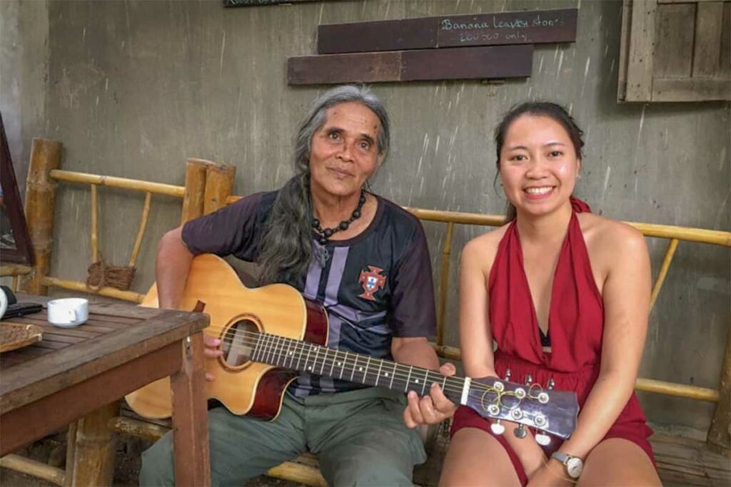 Nhung Phung van het Local Vietnam team samen met een lokale man die gitaar speelt in een etnisch minderhedendorp in Kon Tum in de centrale hooglanden van Vietnam