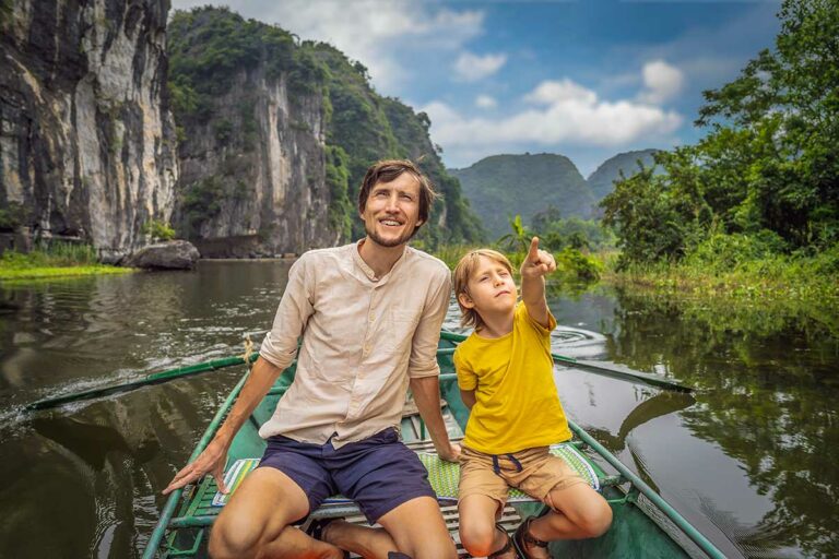 Vader en zoon in Ninh Binh tijdens Trang An boottocht tussen steile kalkstenen rotsen