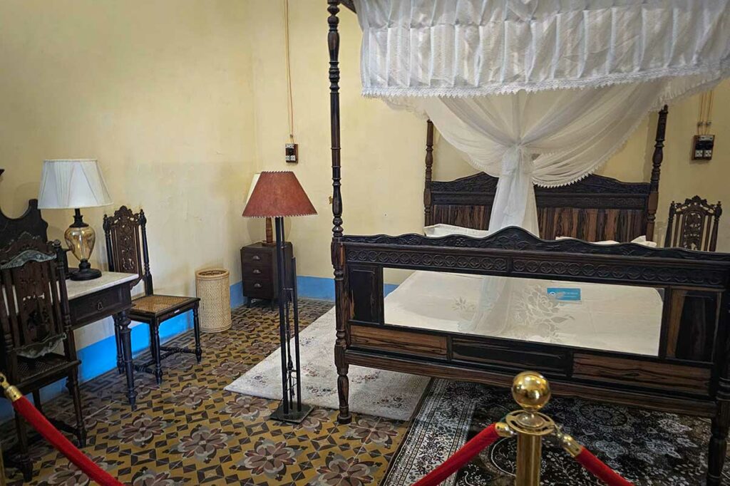 Slaapkamer in het Palace of the Island Governor op Con Dao met antiek hemelbed en koloniale inrichting uit de Franse periode