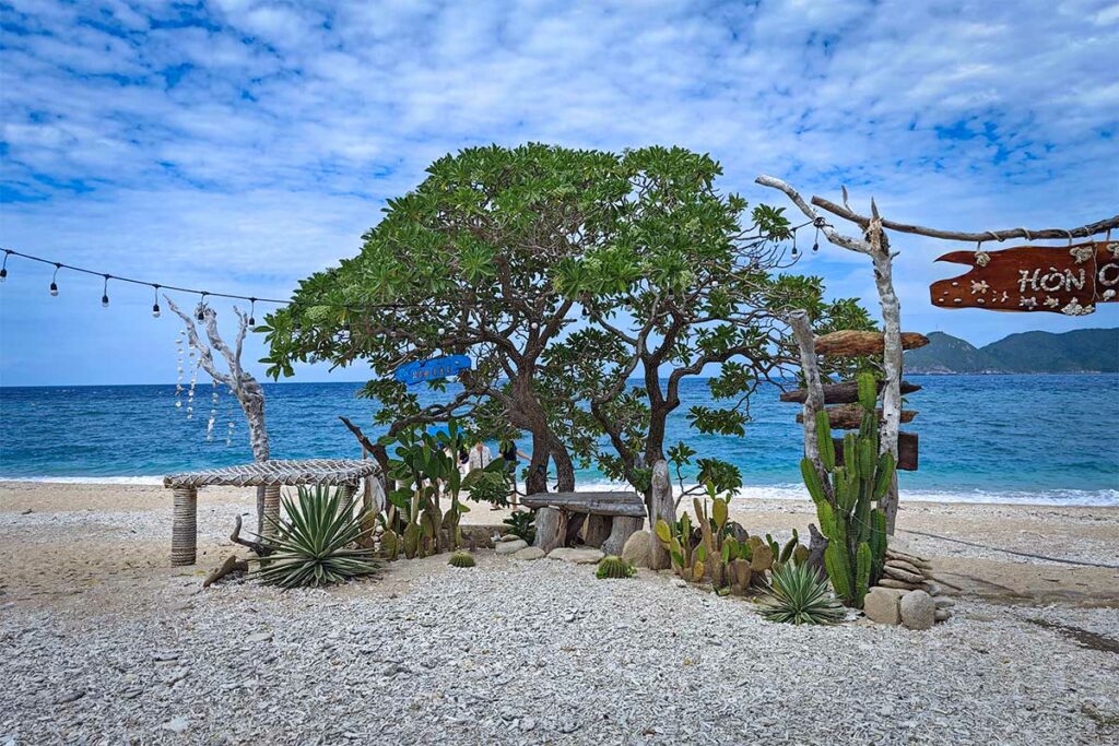 Rustig strand op Hon Cau Island in Con Dao met helder water, zandstrand en eenvoudige strandhutten aan de rand van de jungle. Rustig strand op Hon Cau Island in Con Dao met helder blauw water, witte kiezels en een kleine strandopstelling met planten en houten decoratie.