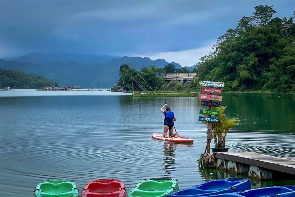 Persoon op een sup board op Hoa Binh Lake bij Mai Chau Floating House met bergen op de achtergrond
