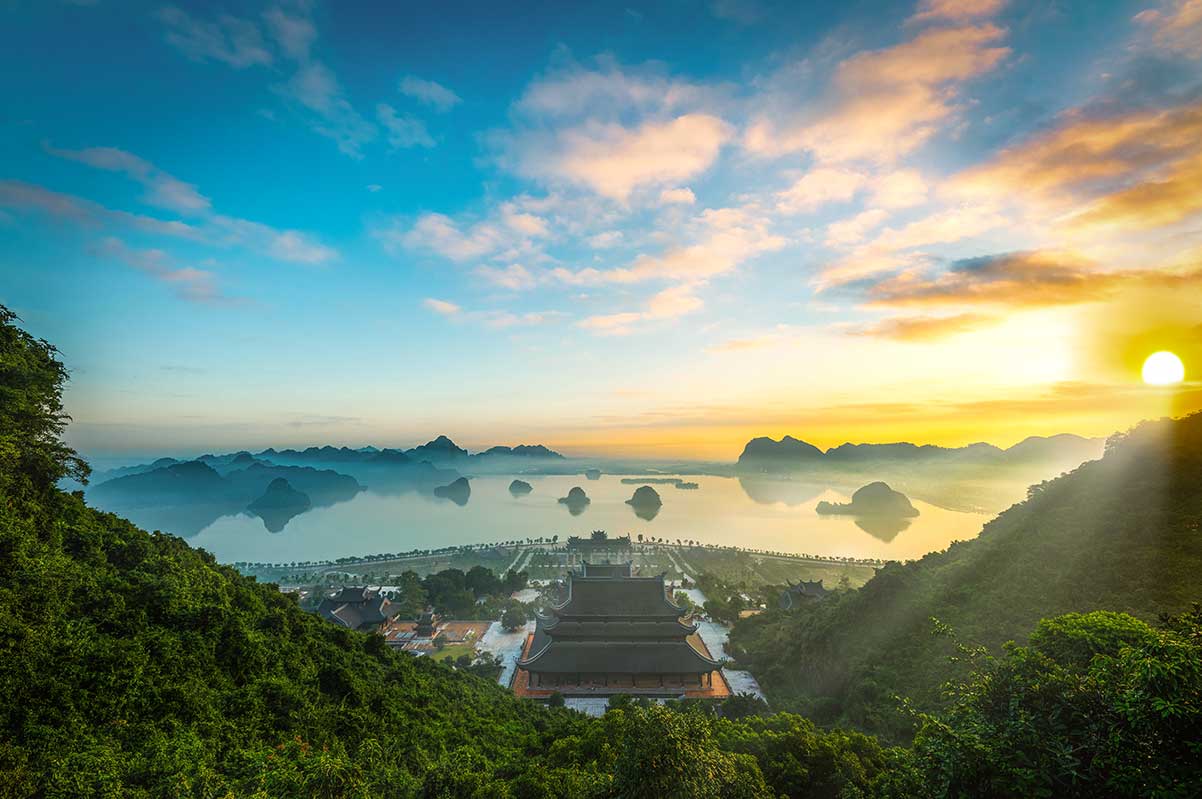 Tam Chuc Pagoda tempelcomplex bij zonsondergang met uitzicht over het meer en kalkstenen bergen