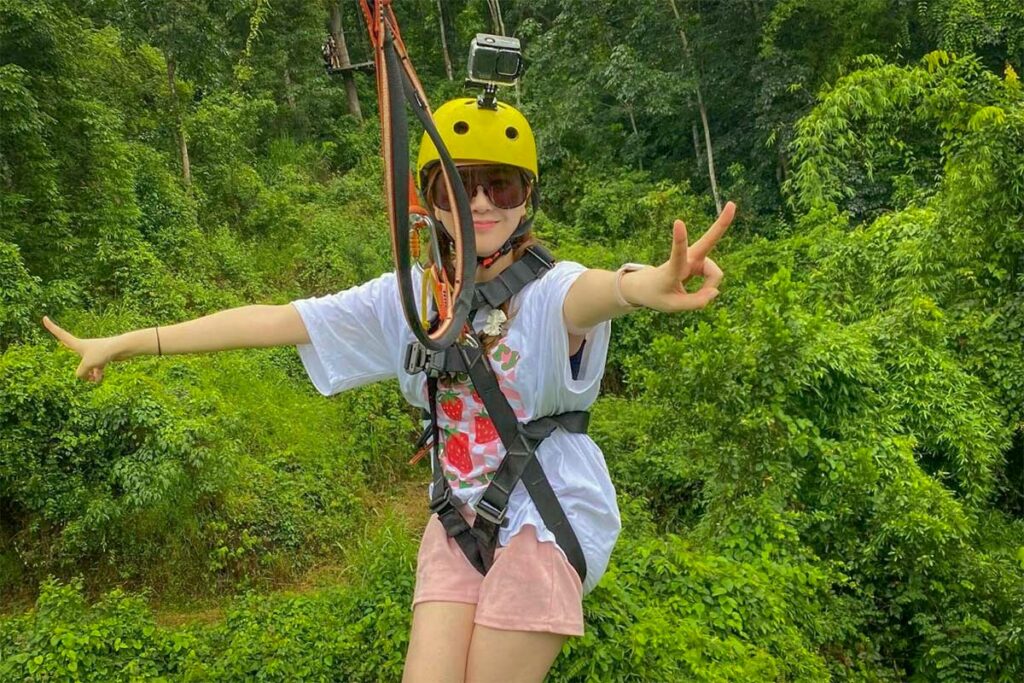 Bezoeker aan het ziplinen in Kong Forest Adventure Park bij Cam Ranh, midden in het groene junglelandschap.