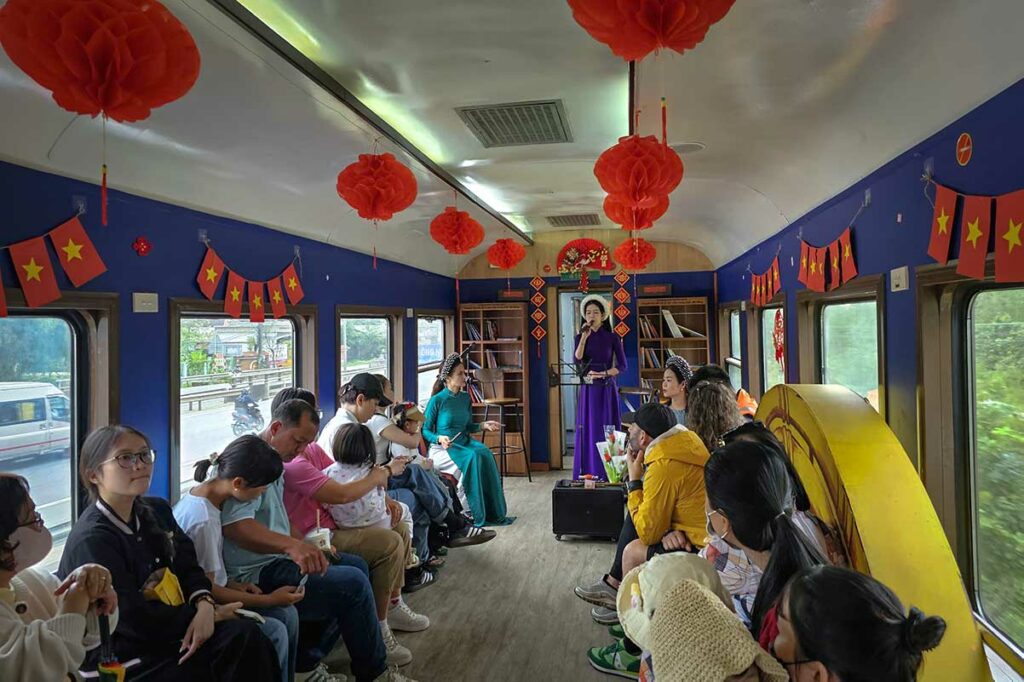 Traditionele Vietnamese muziekoptreden in de Heritage Train tussen Hue en Da Nang met passagiers in een versierde wagon
