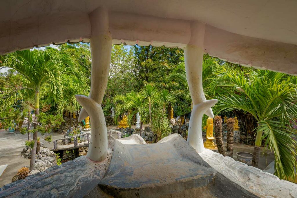 Binnenplaats van Tu Van Pagoda in Cam Ranh met tropische tuin, boeddhabeelden en unieke architectuur.