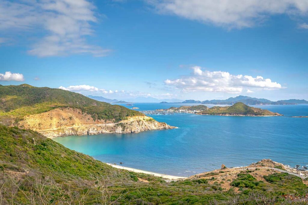 Panoramisch uitzicht over de kust bij Cam Ranh richting Ninh Thuan, met kronkelende kustweg, heuvels en helderblauwe zee.