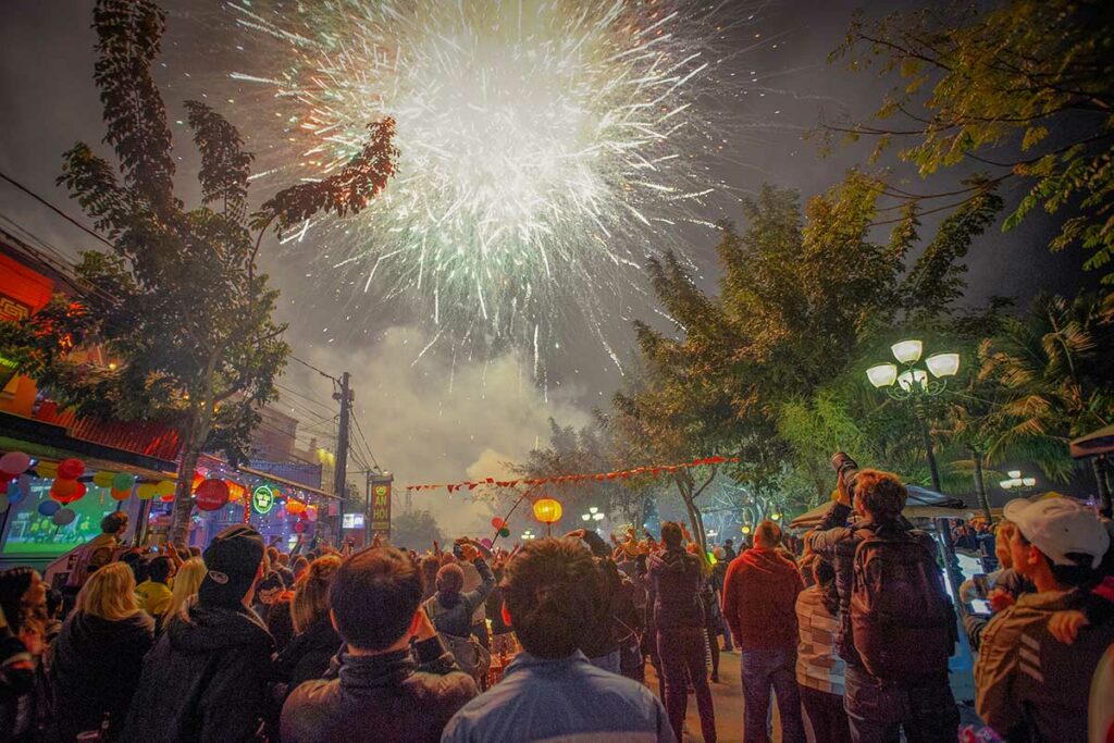 Vuurwerk en feestelijke sfeer tijdens Vietnamees nieuwjaar in Hoi An met mensen die naar de lucht kijken tijdens de Tet-viering