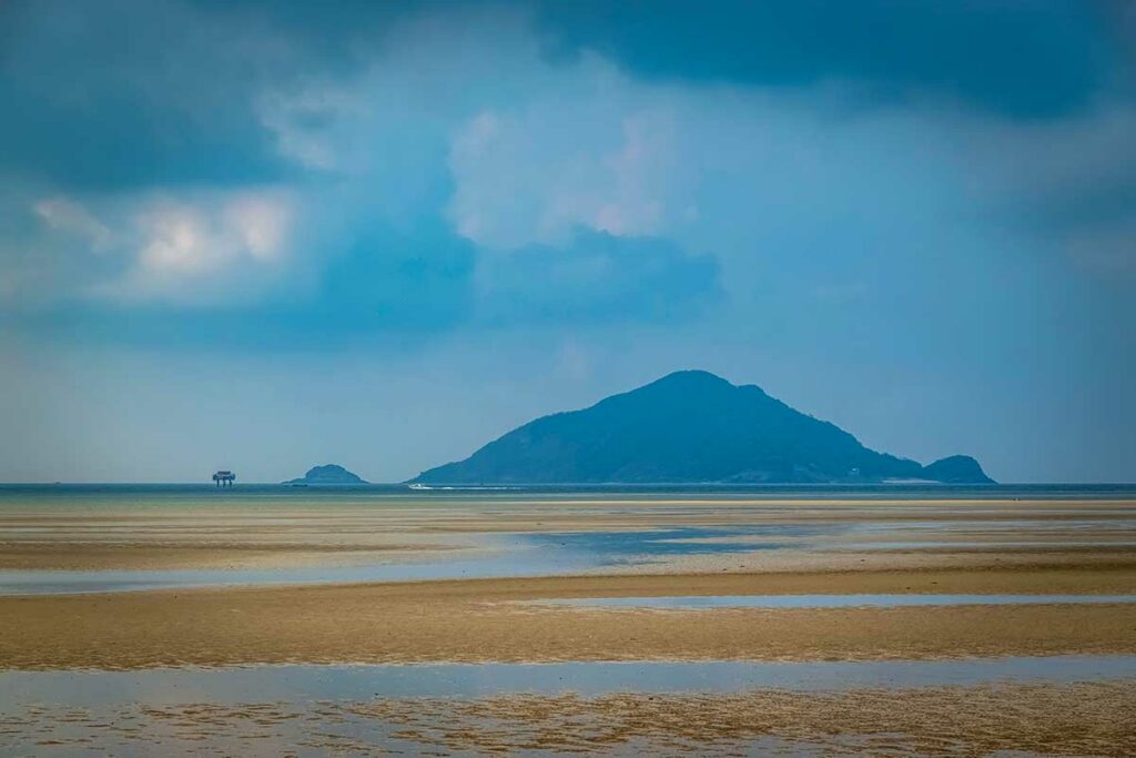 Lo Voi Beach in Con Son, Con Dao met brede zandvlakte bij laag water en uitzicht op eilanden in de verte.