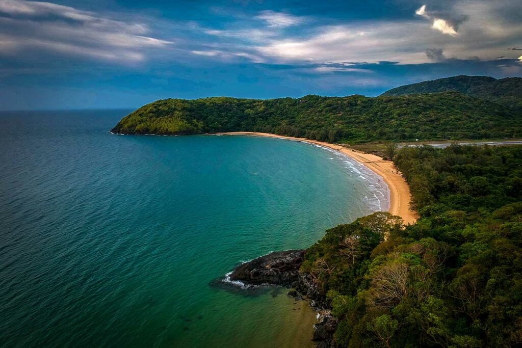 Luchtfoto van Dam Trau Beach in Con Dao met een brede baai, groen begroeide heuvels en helder zeewater.