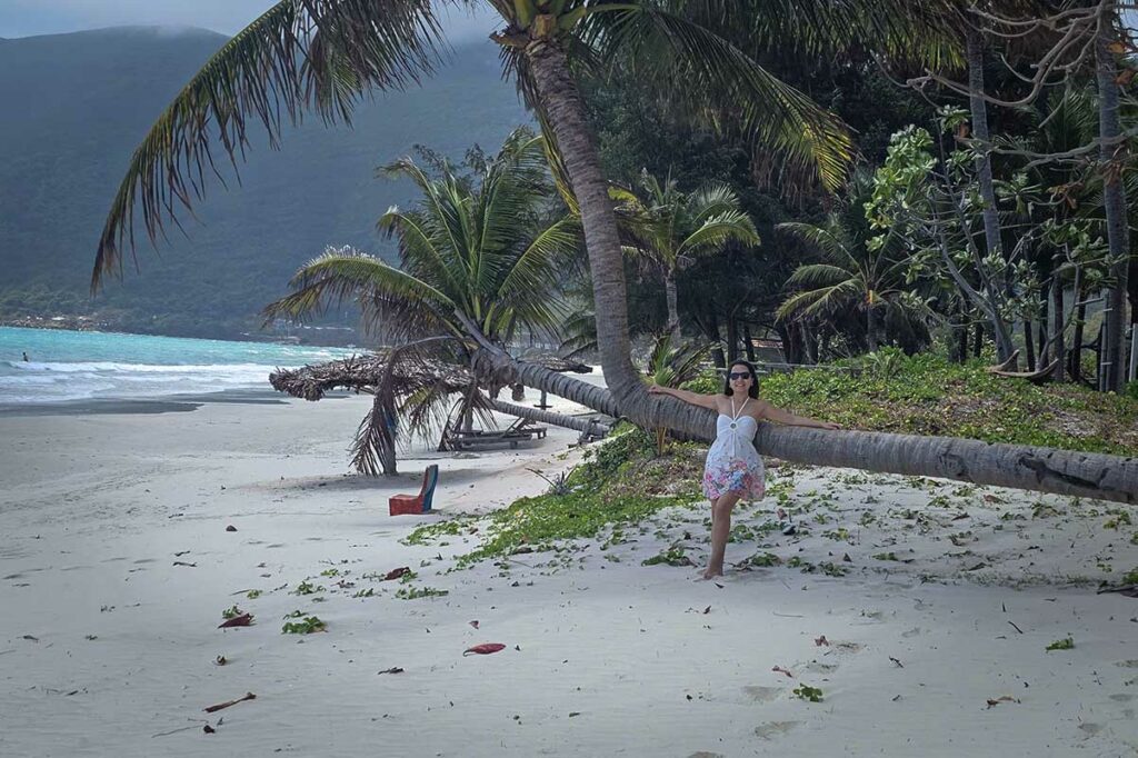 Palmbomen en ligbedden op het strand van An Hai Beach in Con Dao met uitzicht op zee en bergen langs de kust.