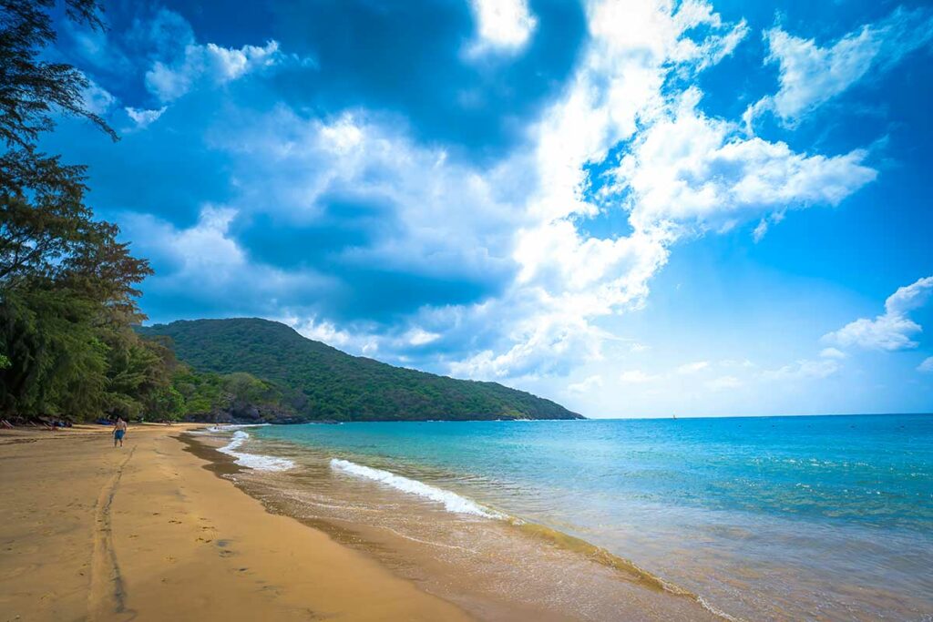 Dam Trau Beach in Con Dao met lang zandstrand, helder water en bergen langs de kustlijn.