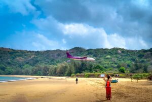Vliegtuig dat laag over Dam Trau Beach in Con Dao vliegt tijdens landing, met uitgestrekt zandstrand en bergen erachter.