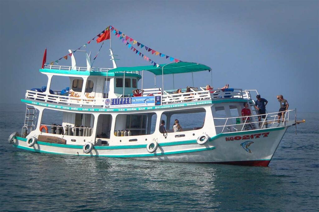 Duikboot van Flipper Diving Club voor anker op het heldere water bij Phu Quoc met duikers aan boord — Flipper Diving Club is een van de bekendste duikscholen voor wie wil duiken bij Phu Quoc