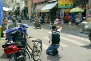 Deelnemer van Het Perfecte Plaatje op Reis fotografeert knielend het brommerverkeer in Ho Chi Minh City, Vietnam
