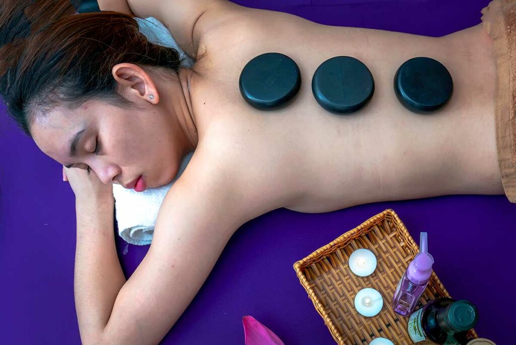 Vrouw ligt ontspannen met drie hete basaltstenen op haar rug tijdens een hotstonemassage in Vietnam