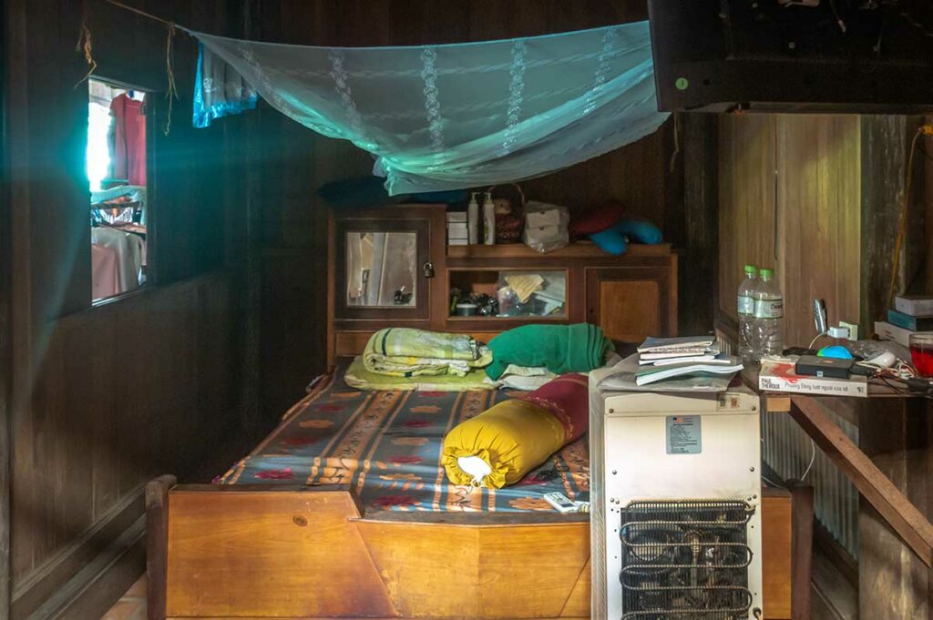 Slaapkamer in een eenvoudig huis in Vietnam met een klamboe boven het bed als bescherming tegen muggen