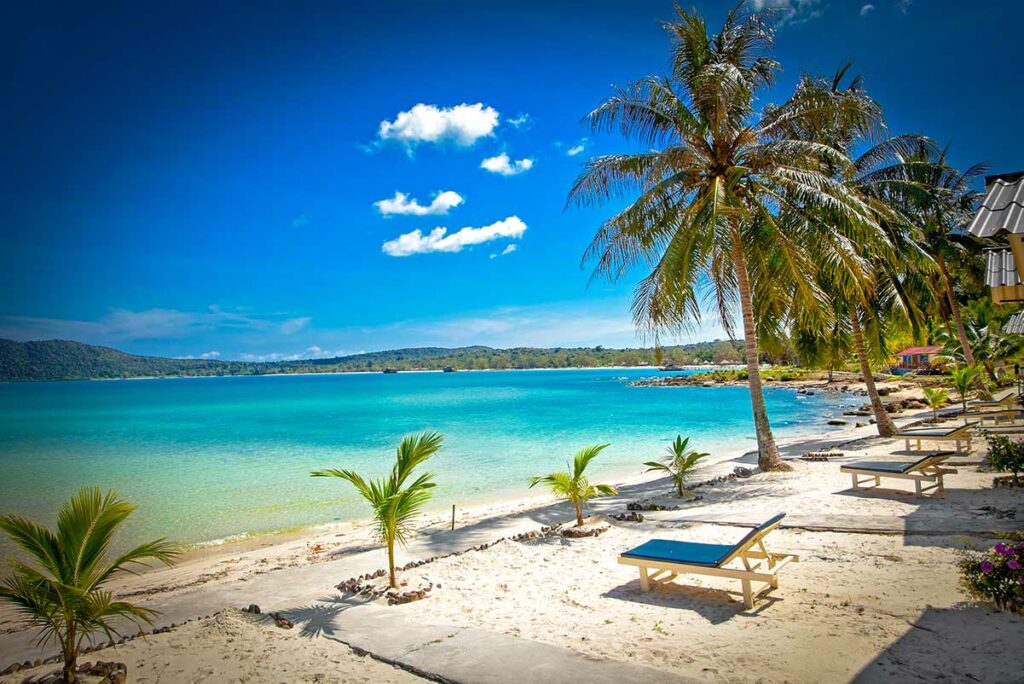 Wit zandstrand op Koh Rong Samloem in Cambodja met turquoise water, palmbomen en ligstoelen op een zonnige dag