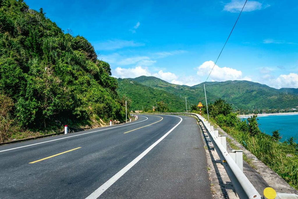 Lege kustweg in Phu Yen die slingert langs groene heuvels aan de ene kant en turquoise zee aan de andere kant — de kustroute door Phu Yen is een van de mooiste rijroutes in centraal Vietnam