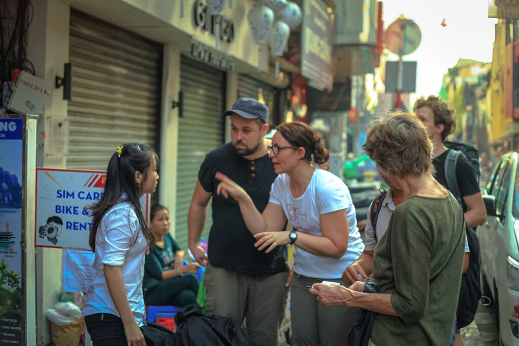 Westerse reizigers in gesprek met een lokale Vietnamese gids op straat, het inschakelen van een lokale gids is een van de manieren om duurzaam en verantwoord te reizen in Vietnam