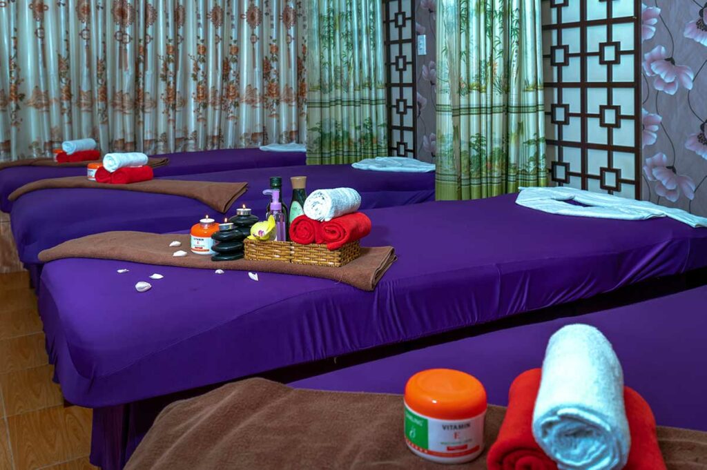 Klaargemaakt massagesalon in Vietnam met paarse bedden, opgerolde handdoeken en massageolie klaar voor gebruik