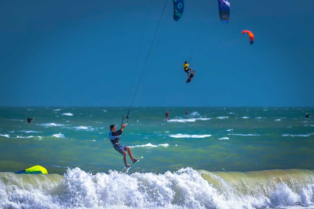 Kitesurfer springt hoog boven de branding in Mui Ne terwijl op de achtergrond een andere surfer eveneens de lucht in gaat — Mui Ne trekt kitesurfers uit de hele wereld