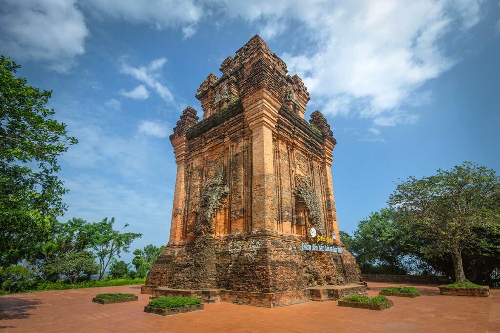 De Nhan Tower, een goed bewaarde Cham tempeltoren uit de elfde eeuw op een heuvel bij Tuy Hoa, omgeven door bomen en een blauwe lucht — een van de weinig bezochte Cham monumenten in centraal Vietnam