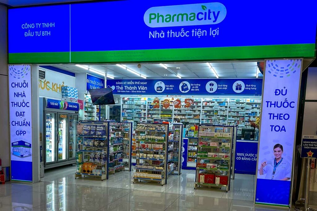 Filiaal van apotheekketen Pharmacity in Vietnam met een verlichte blauwe gevel en schappen vol medicijnen