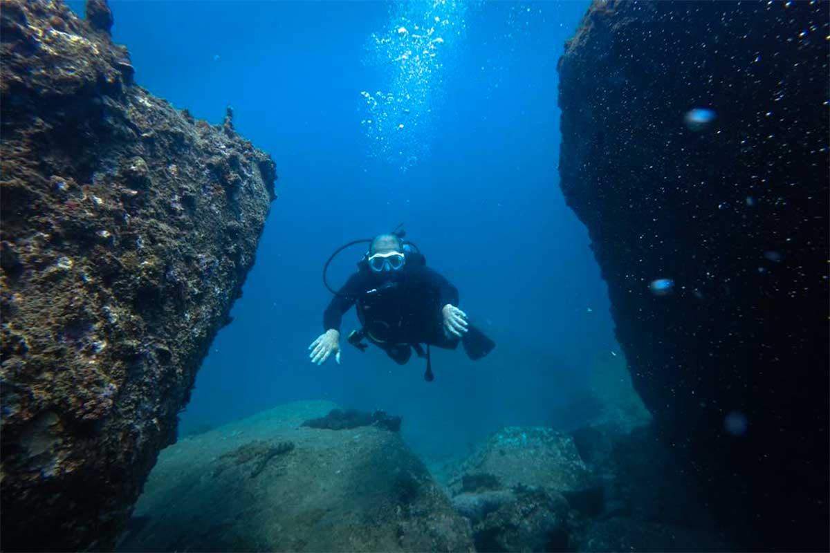 Scubaduiker zweeft tussen twee grote rotsblokken op de bodem van de zee bij Hon Mun, Nha Trang — de gevarieerde rotsformaties maken Hon Mun tot het populairste duikgebied bij Nha Trang
