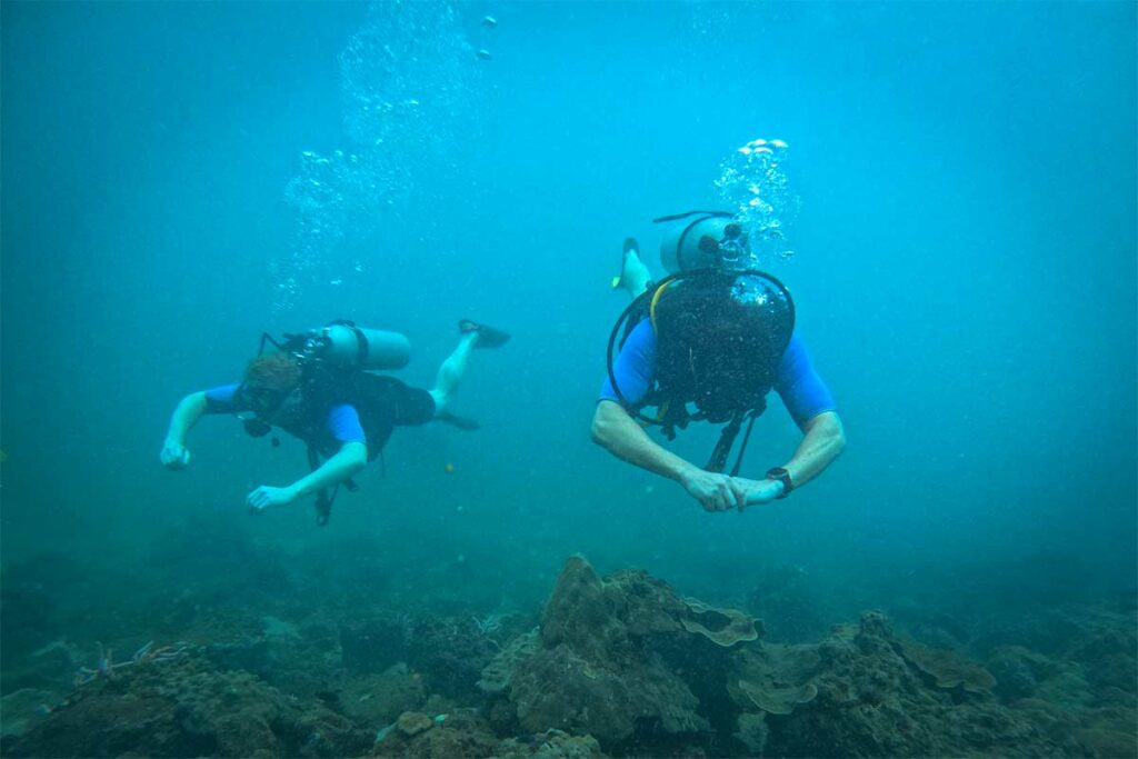 Twee scubaduikers zwemmen over een koraalrif bij Phu Quoc — het zicht is hier doorgaans beperkt in vergelijking met Nha Trang, maar de riffen bieden een gevarieerd onderwaterleven