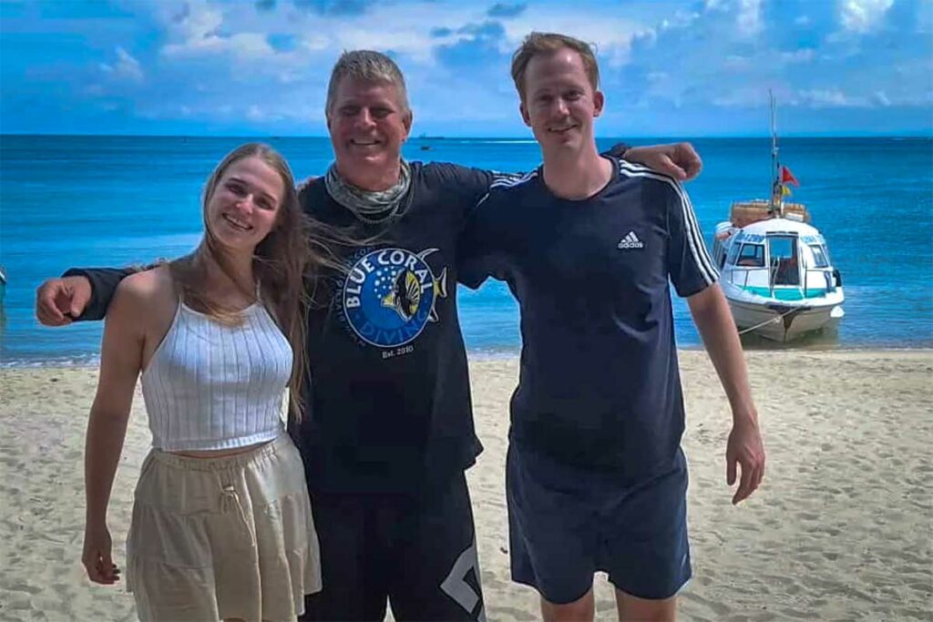 Duikinstructeur van Blue Coral Diving poseert met twee tevreden klanten op het strand bij de Cham eilanden — een van de bekende duikscholen voor wie wil duiken bij Hoi An