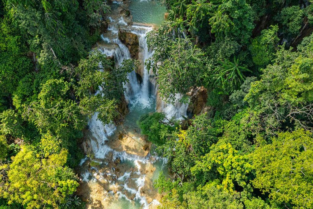 Luchtfoto van de Tat Kuang Si watervallen bij Luang Prabang in Laos, met meerdere trappen van turquoise water omringd door dicht tropisch regenwoud